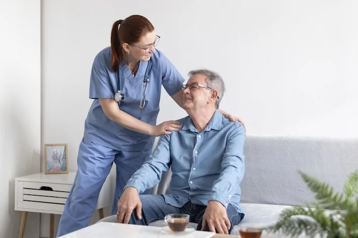 Caregiver providing friendly assistance to an elderly man at home, illustrating In-Home Care Cost Arizona 2026 and personalized senior care services in Arizona.